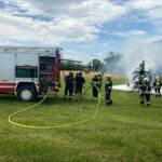 Rundballenpresse und Strohfeld in Flammen