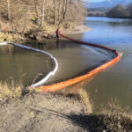 Die Feuerwehr errichtet eine Ölsperre am Bach