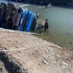 Ein Feuerwehrtaucher untersucht den LKW auf Schadstoffaustritt