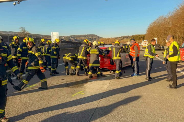 Der beschädigte PKW wird mit Muskelkraft von der Autobahn entfernt