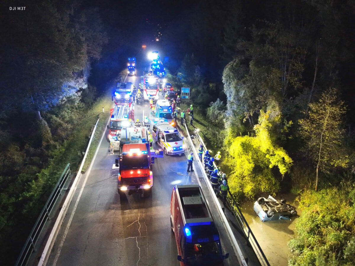 PKW landet im Bach, Person eingeklemmt